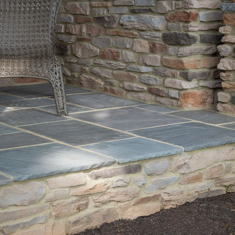 patio floor with natural stone paving and walls covered with veneer