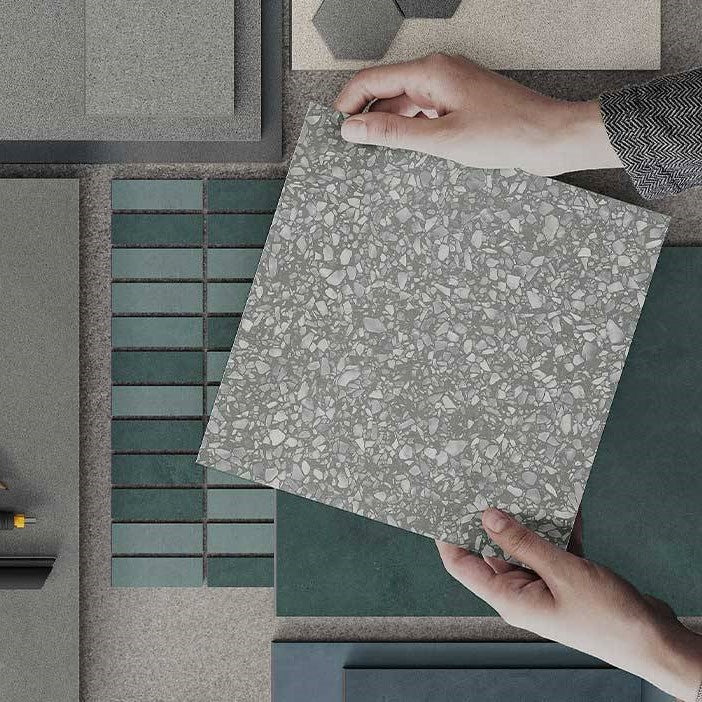 showcasing various porcelain product types with hands holding gray square porcelain tile which has terrazzo look