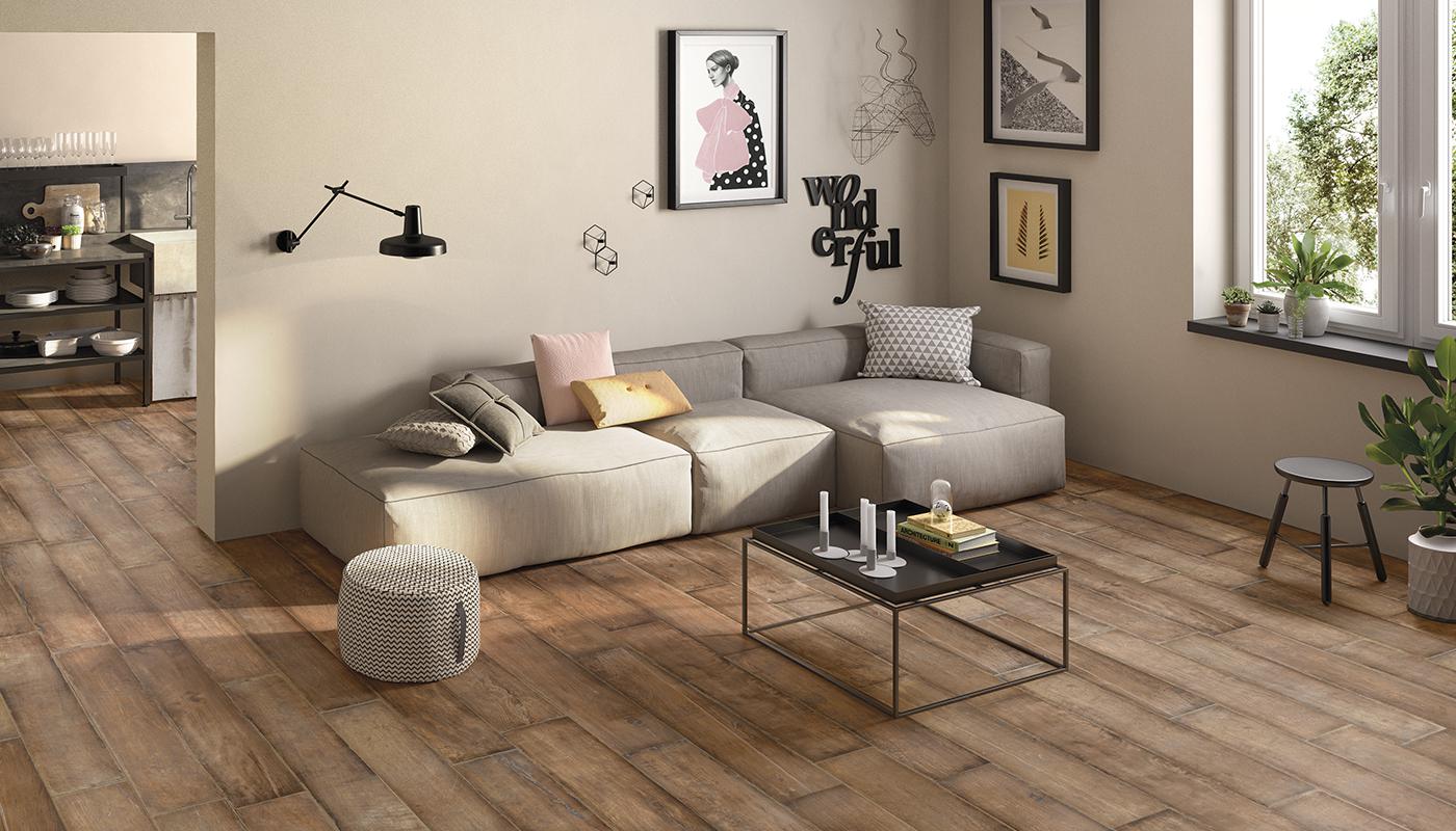Modern living room featuring 20Twenty Italian porcelain tile flooring by Emilceramica, showcasing a stylish interior with a beige sectional sofa, wooden coffee table, and decorative wall art.