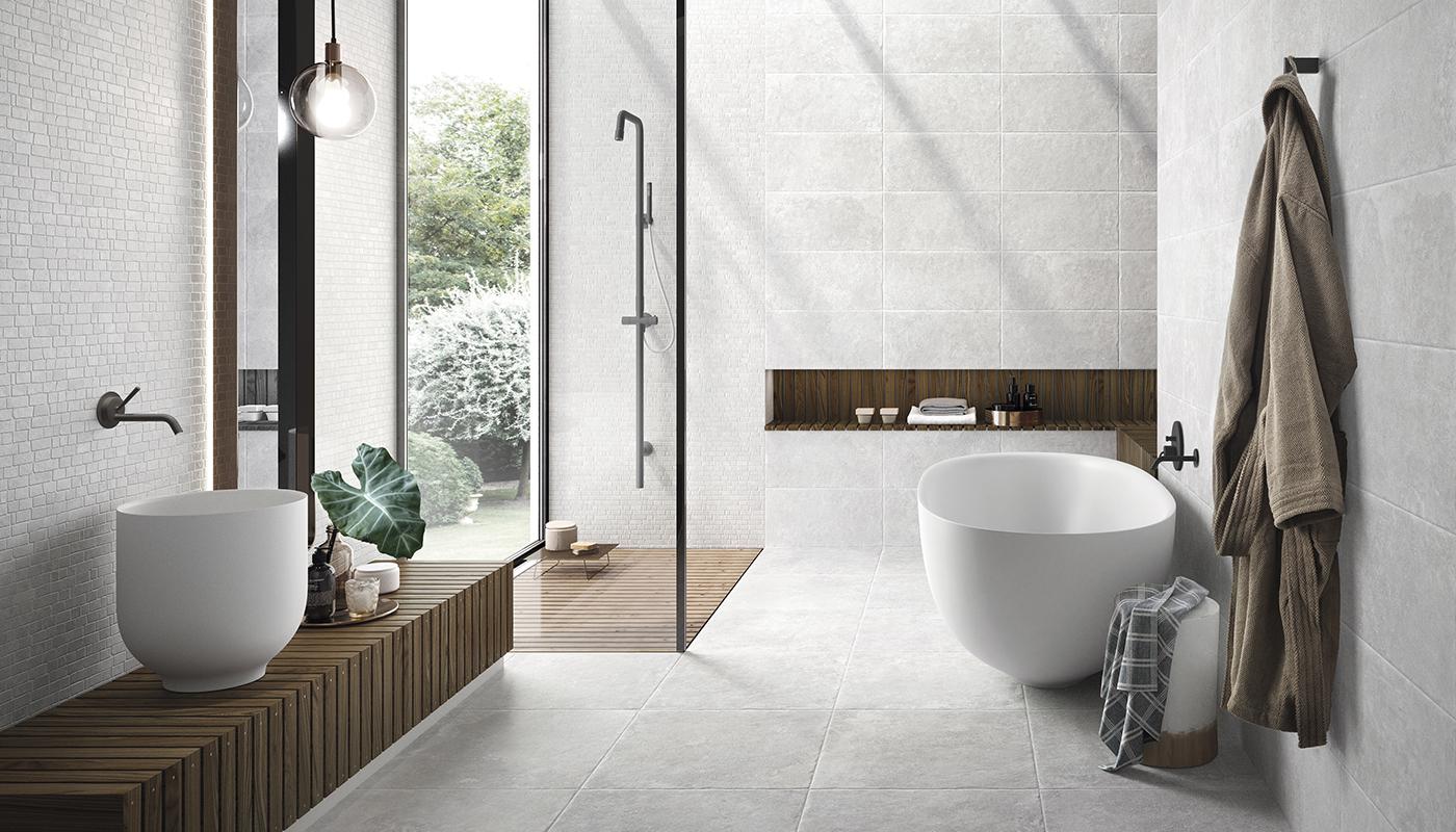 Elegant modern bathroom featuring Chateau Italian porcelain tile collection by Emilceramica with freestanding bathtub, wooden accents, and large format tiles.