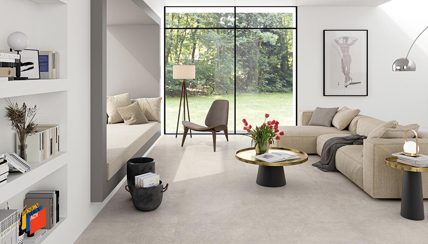 Modern living room with high-end Italian porcelain tile flooring from Emilceramica Landscape collection, featuring elegant furniture and large windows with garden view.