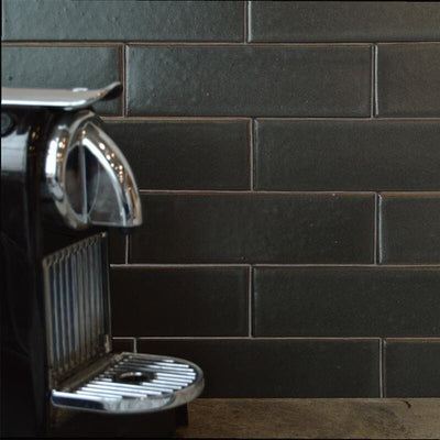 Close-up of dark gray tile backsplash in kitchen with modern espresso machine on countertop.
