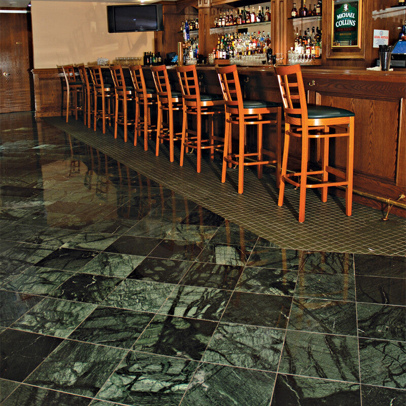 Bar area with wooden high stools, a long counter, and a reflective green marble tile floor. Luxurious feel with deep green color and natural veining.