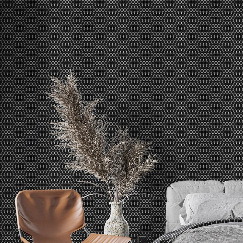 Modern black hexagon mosaic tile wall with dried pampas grass vase, brown leather chair, and white bed with neutral bedding.