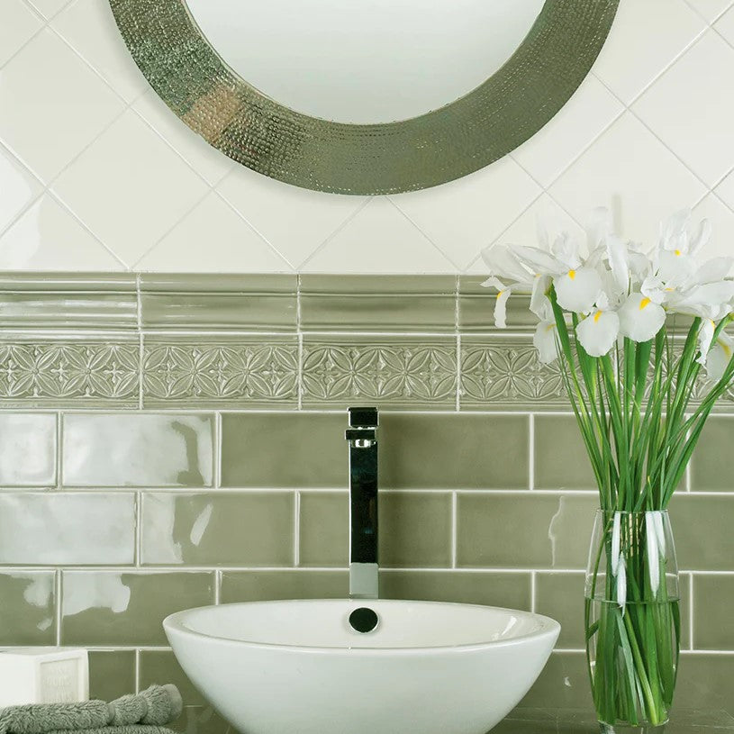 Elegant bathroom featuring Adex Studio Ceramic Tiles in Fern, with a decorative border adding a refined touch, complemented by a contemporary vessel sink, fresh flowers, and a circular mosaic mirror.