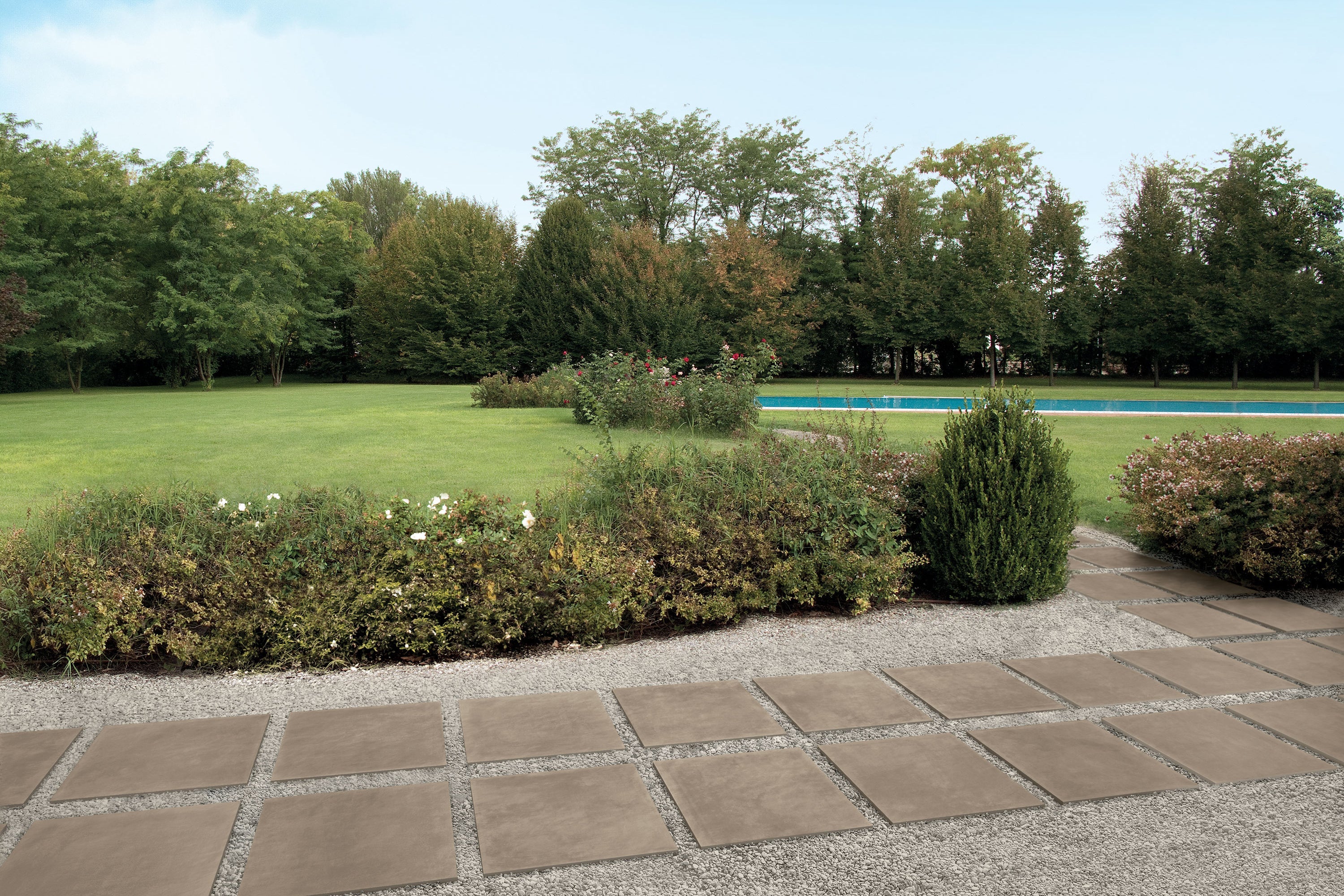 Porcelain tile collection with concrete look by Surface Group displayed in outdoor setting with pool and garden