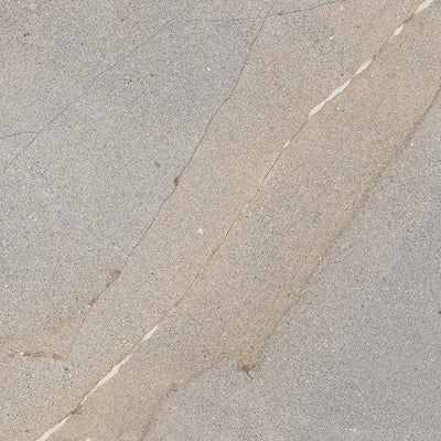 A close-up of a porcelain tile with a realistic stone-look design, featuring a subtle blend of light beige and cream colors with fine grain detailing and sporadic darker veining across the surface.