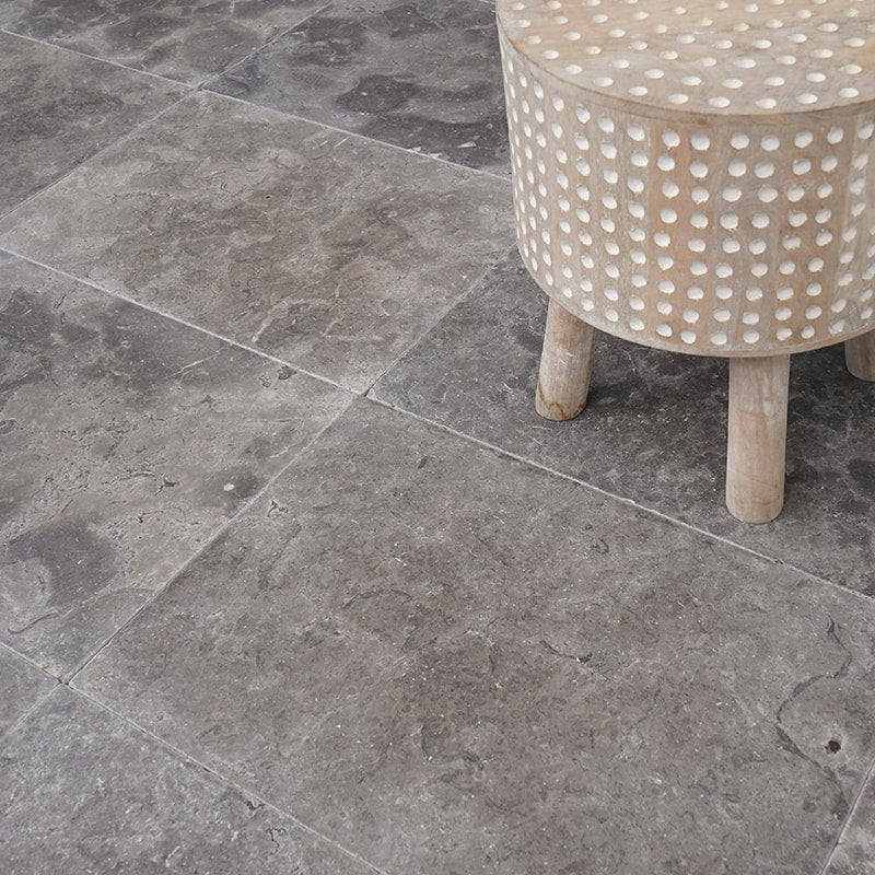 Assortment of gray limestone tiles and slabs from the Gray Limestone Collection, showcasing various shades and textures, arranged to demonstrate their elegance and adaptability in enhancing interior designs.