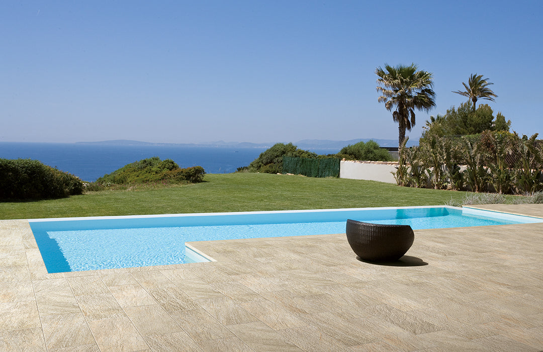 Luxury porcelain tile collection by Surface Group featuring elegant beige tiles in outdoor setting with infinity pool and ocean view.