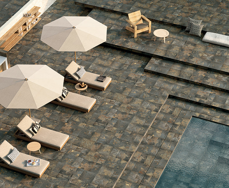 Porcelain slate tile collection from Surface Group featuring natural stone look in outdoor patio setting with poolside loungers and umbrellas.