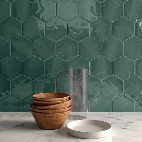 Chic kitchen space enhanced by the hexagonal Anatolia Teramoda Glazed Ceramic tiles in a rich emerald hue, paired with natural wood accents and a clear water pitcher, embodying a blend of artisan elegance and modern design