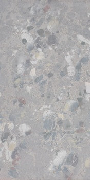 A textured terrazzo-inspired porcelain tile with raw, unpredictable chips in soft gray, exuding industrial elegance and material depth.